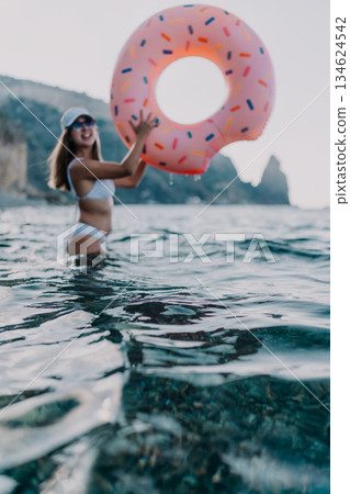 Woman, swim, donut. Happy young woman holding a donut float in the ocean, enjoying summer vacation. 134624542
