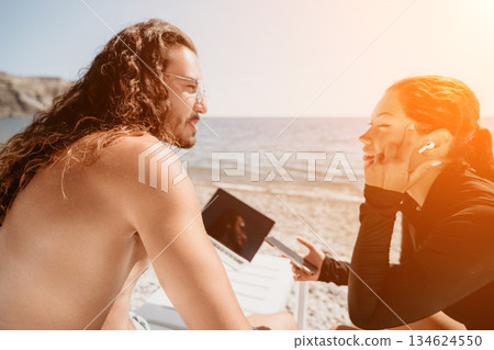 Couple Beach Laptop - Happy couple on the beach using a laptop on a sunny day. Couple Beach Laptop - Happy couple on the beach using a laptop on a sunny day. 134624550