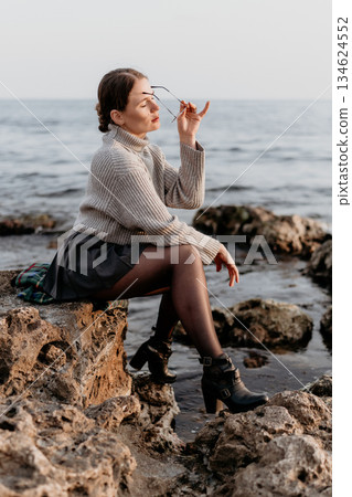 Woman Beach Fashion Photography: Coastal autumn portrait, stylish attire, serene ocean view. Woman Beach Fashion Photography: Coastal autumn portrait, stylish attire, serene ocean view. 134624552