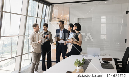 Five serious focused teammates gathered in skyscraper office meeting room Five serious focused teammates gathered in skyscraper office meeting room 134624712