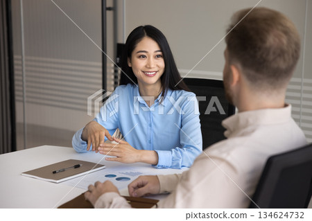 Attractive Asian businesswoman engaged in formal conversation with man colleague 134624732