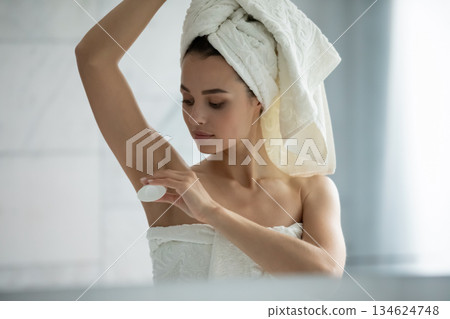 Headshot happy young lady applying solid deodorant stick to underarms Headshot happy young lady applying solid deodorant stick to underarms 134624748