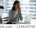 Young woman sitting by laptop with closed eyes folded palms 134624749