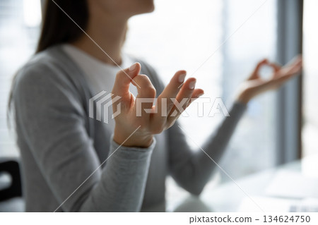 Cropped closeup young female student worker meditating at work desk 134624750