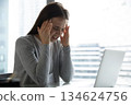 Stressed nervous young businesswoman suffering from headache sitting by notebook 134624756