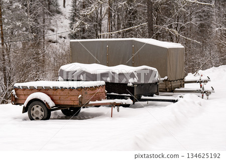 Car trailers in a snowy parking lot in the forest in winter. 134625192
