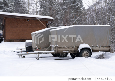 Car trailers in a snowy parking lot in the forest in winter. 134625199