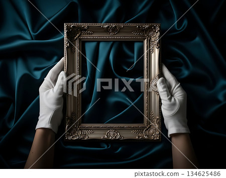 Ornate antique picture frame held by hands in white gloves against dark teal silk fabric Ornate antique picture frame held by hands in white gloves against dark teal silk fabric 134625486