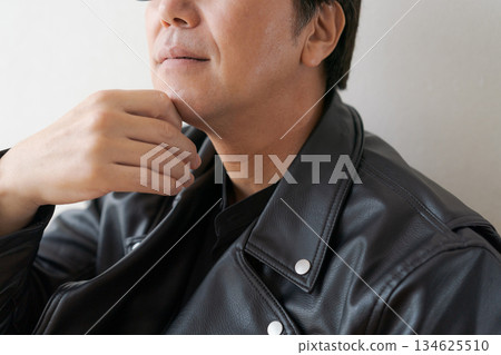 A man in his 50s wearing glasses and a leather jacket 134625510