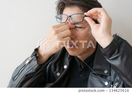 A man in his 50s holding the corners of his eyes A man in his 50s holding the corners of his eyes 134625618