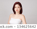 A beautiful young Asian woman with clean, fresh skin against a grey background. Skincare, facial treatment, cosmetology, beauty, and spa. An elegant portrait of an Asian woman. 134625642