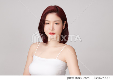 A beautiful young Asian woman with clean, fresh skin against a grey background. Skincare, facial treatment, cosmetology, beauty, and spa. An elegant portrait of an Asian woman. A beautiful young Asian woman with clean, fresh skin against a grey background. Skincare, facial treatment, cosmetology, beauty, and spa. An elegant portrait of an Asian woman. 134625642