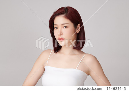 A beautiful young Asian woman with clean, fresh skin against a grey background. Skincare, facial treatment, cosmetology, beauty, and spa. An elegant portrait of an Asian woman. A beautiful young Asian woman with clean, fresh skin against a grey background. Skincare, facial treatment, cosmetology, beauty, and spa. An elegant portrait of an Asian woman. 134625643