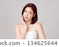 A beautiful young Asian woman with clean, fresh skin against a grey background. Skincare, facial treatment, cosmetology, beauty, and spa. An elegant portrait of an Asian woman. 134625644