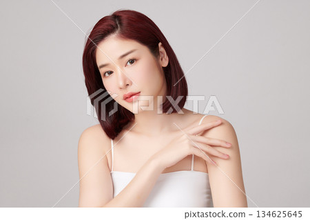 A beautiful young Asian woman with clean, fresh skin against a grey background. Skincare, facial treatment, cosmetology, beauty, and spa. An elegant portrait of an Asian woman. A beautiful young Asian woman with clean, fresh skin against a grey background. Skincare, facial treatment, cosmetology, beauty, and spa. An elegant portrait of an Asian woman. 134625645