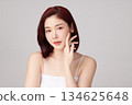 A beautiful young Asian woman with clean, fresh skin against a grey background. Skincare, facial treatment, cosmetology, beauty, and spa. An elegant portrait of an Asian woman. 134625648