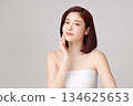 A beautiful young Asian woman with clean, fresh skin against a grey background. Skincare, facial treatment, cosmetology, beauty, and spa. An elegant portrait of an Asian woman. 134625653