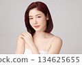 A beautiful young Asian woman with clean, fresh skin against a grey background. Skincare, facial treatment, cosmetology, beauty, and spa. An elegant portrait of an Asian woman. 134625655