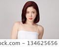 A beautiful young Asian woman with clean, fresh skin against a grey background. Skincare, facial treatment, cosmetology, beauty, and spa. An elegant portrait of an Asian woman. 134625656
