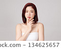 A beautiful young Asian woman with clean, fresh skin against a grey background. Skincare, facial treatment, cosmetology, beauty, and spa. An elegant portrait of an Asian woman. 134625657