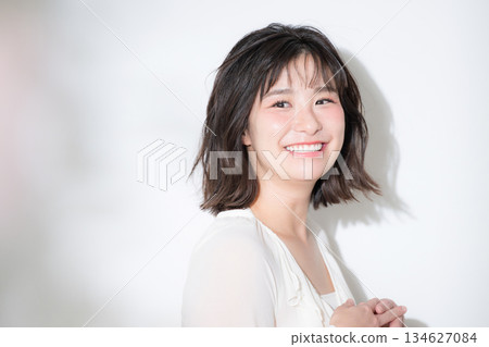 一張美麗的特寫照片，展現了一位快樂、年輕、氣質柔和的女性，她笑容燦爛，神采奕奕，充滿喜悅。 134627084