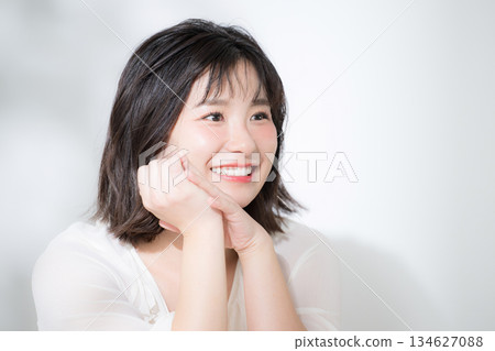 一張年輕女性的特寫美照，她神態柔和，目光清澈明亮，面帶微笑，一隻手輕輕撫摸著臉頰。 134627088