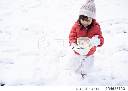 一個戴著針織帽的女孩在雪地公園玩耍 134628130