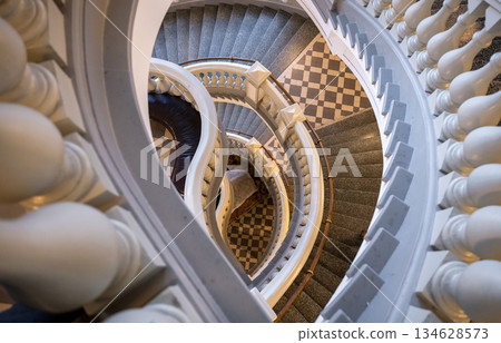 Elegant spiral staircase with classic balustrade and tiled floor Elegant spiral staircase with classic balustrade and tiled floor 134628573