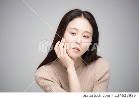 一位面露憂鬱的美麗女子,手托著下巴,若有所思地望著鏡頭。 一位面露憂鬱的美麗女子,手托著下巴,若有所思地望著鏡頭。 134628959