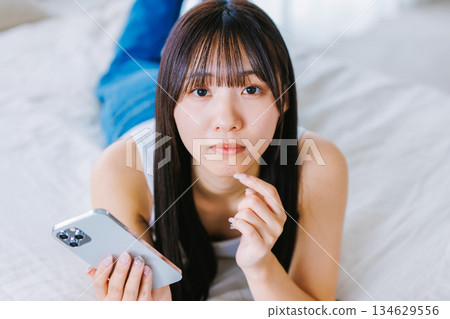 在床上使用智能手機的年輕女子 134629556