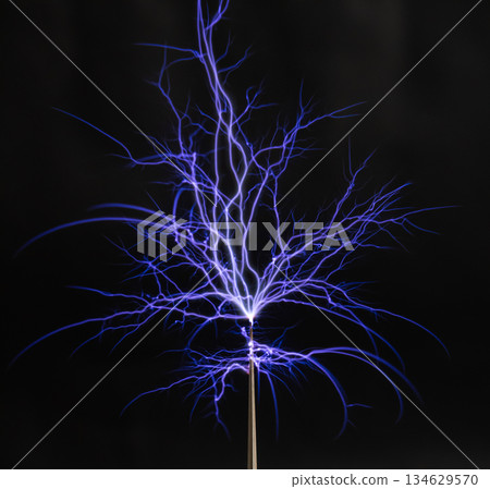 Blue lightning bolts of electrostatic discharge from the tip of a Tesla coil against 134629570