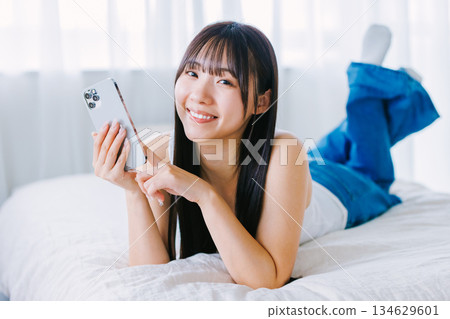 在床上使用智能手機的年輕女子 134629601
