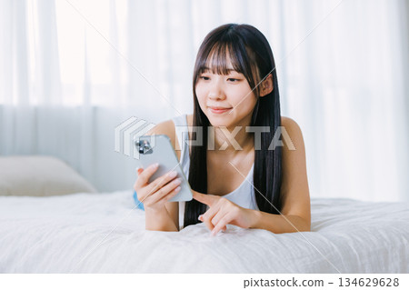 Young woman using a smartphone in bed 134629628