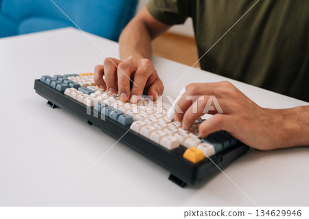 Closeup of unrecognizable man hands typing on mechanical keyboard featuring finger splint, representing focus on productivity, health and medical condition, injury at desk. 134629946