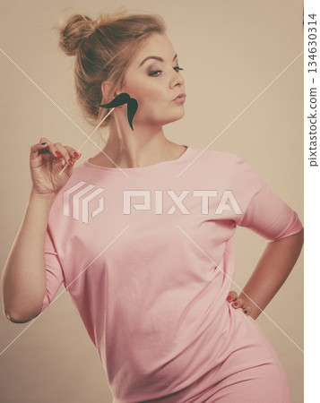 Happy woman holding fake moustache on stick 134630314