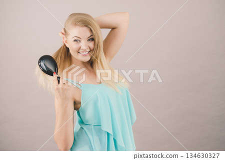 Blonde woman brushing her long hair Blonde woman brushing her long hair 134630327