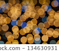 Abstract Bokeh from indoor lighting, Blue with orange with gold and yellow circles spread on  black colored surface, Night city light background for celebration of christmas and holiday season 134630931