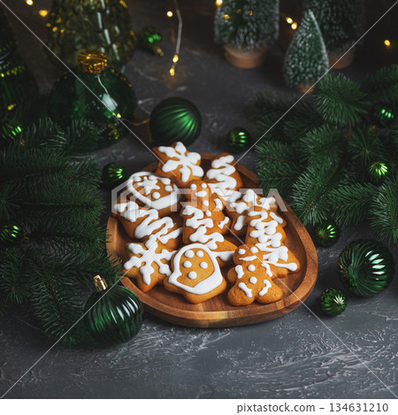 Homemade Decorated Gingerbread Cookies with Icing on Wooden Plate and Pine Decor Homemade Decorated Gingerbread Cookies with Icing on Wooden Plate and Pine Decor 134631210
