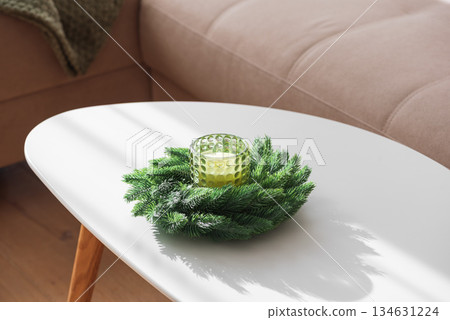 Cozy Living Room with Green Pillows, Knit Blanket, and Christmas Holiday Candle with Fir Wreath 134631224
