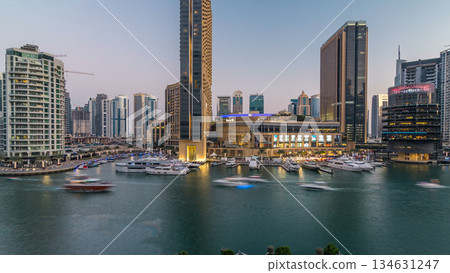 Aerial view of Dubai Marina with shopping mall, restaurants, towers and yachts day to night timelapse, United Arab Emirates. Aerial view of Dubai Marina with shopping mall, restaurants, towers and yachts day to night timelapse, United Arab Emirates. 134631247