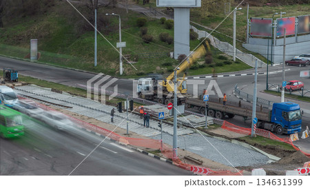 Loader crane for loading and unloading tram rails from truck which stands on a road construction site aerial timelapse 134631399