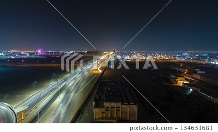 Traffic on a big road junction in Ajman aerial view from rooftop at night timelapse. 134631681
