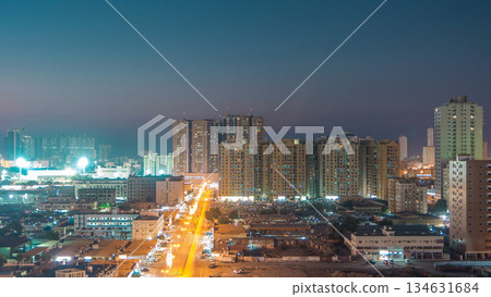 Cityscape with towers in Ajman from rooftop day to night timelapse. United Arab Emirates. 134631684