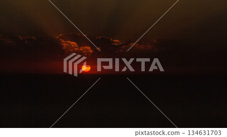 Sunset timelapse view: yellow bright sun disc on natural orange sky background with sun beams and rays of light 134631703