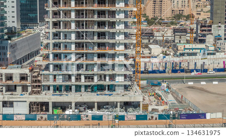 Aerial view of a skyscrapers under construction with huge cranes timelapse in Dubai. 134631975