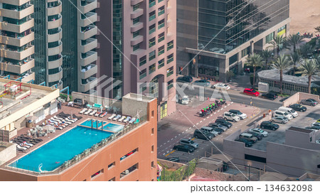 Car parking lot with rooftop swimming pool viewed from above timelapse, Aerial top view. Dubai, UAE Car parking lot with rooftop swimming pool viewed from above timelapse, Aerial top view. Dubai, UAE 134632098