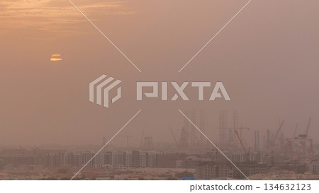 Sunset during sand storm over industry port in Dubai timelapse. 134632123