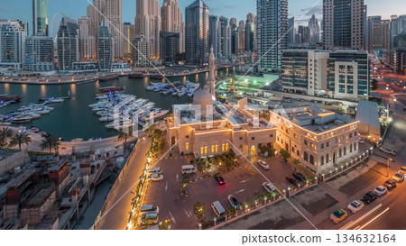 Yachts in Dubai Marina flanked by the Al Rahim Mosque and residential towers and skyscrapers aerial night to day timelapse. Yachts in Dubai Marina flanked by the Al Rahim Mosque and residential towers and skyscrapers aerial night to day timelapse. 134632164