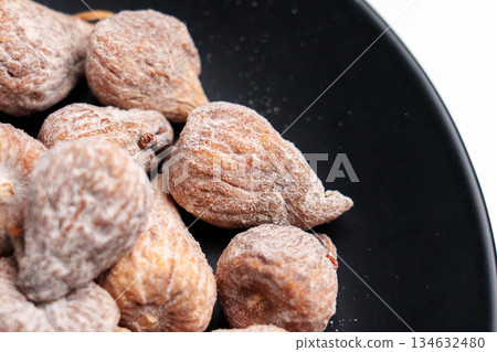 Dried fig dusted with powdered sugar on black ceramic dish close up 134632480