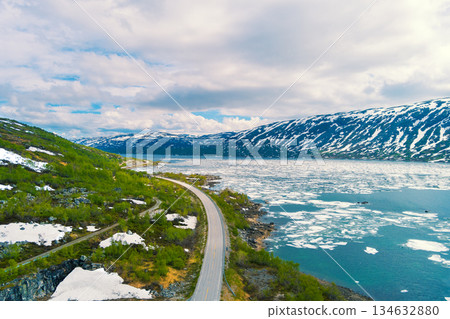 View from above the rocky shore of Breiddalsvatnet Lake. Melting mountain lake and highway. Grotli, Norway 134632880